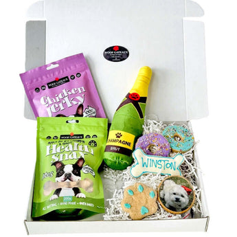 Mixed dog treat box featuring Healthy Dog Treats, Dog Birthday Cake cookies and a fun plush champagne toy.
