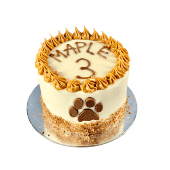 Personalized dog birthday cake for Maple, decorated with a paw print and golden frosting.