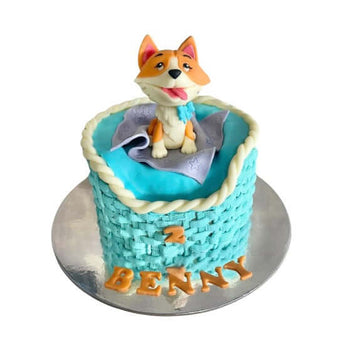 Dog in a Dog-Bed Birthday Cake in dog bed design featuring a cute figurine of a dog and personalized name on top.