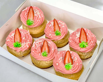 Dog-friendly pupcakes topped with pink frosting, strawberries, and coconut sprinkles for your furry friend.