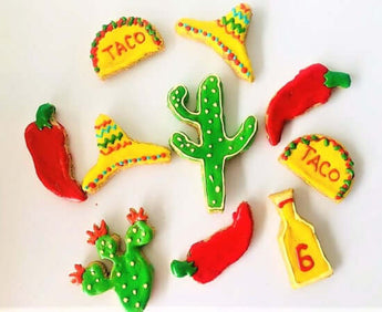Colorful fiesta dog cookies shaped like tacos, cacti, and chili peppers, perfect for a fun celebration!