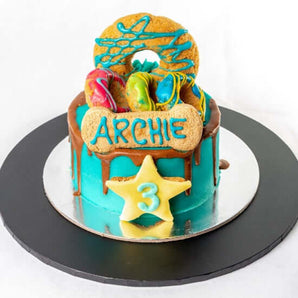 Colorful 5" dog birthday cake decorated with cookies and candies for a celebratory pet occasion.